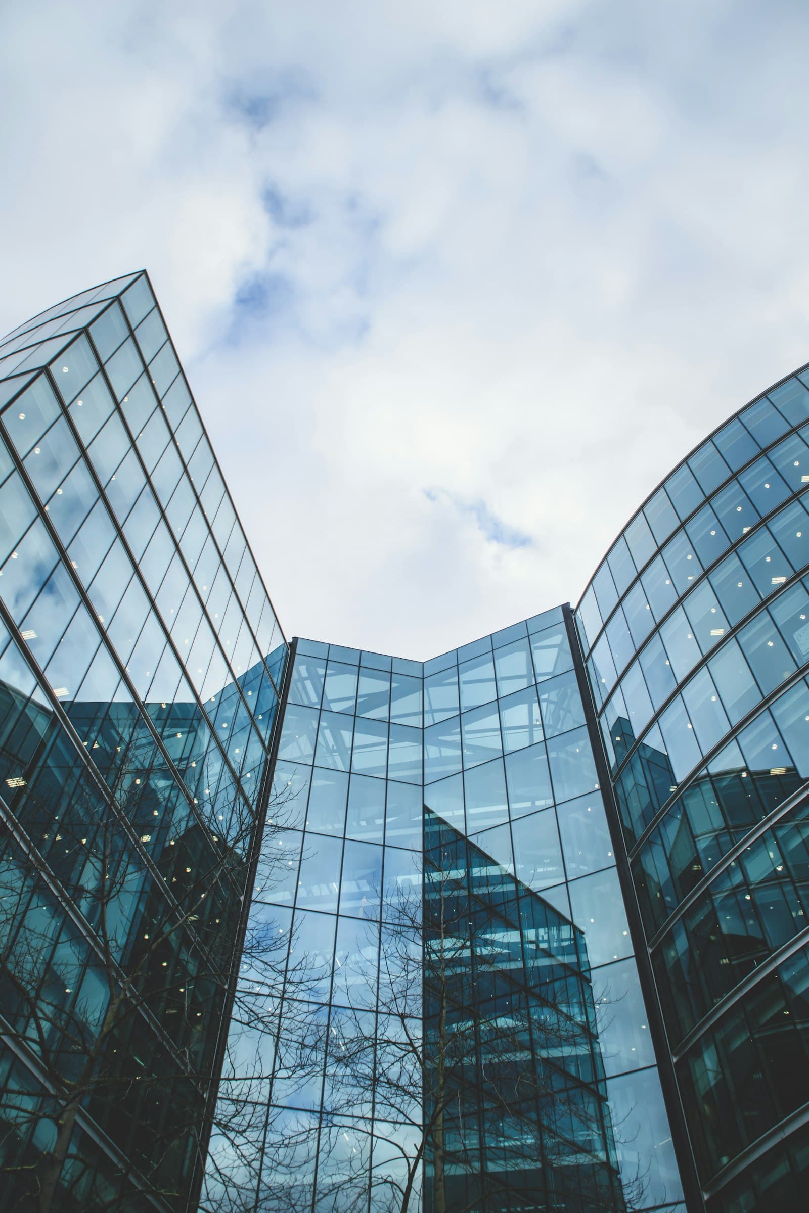 Twin glass corporate towers converging against the sky, seen from below