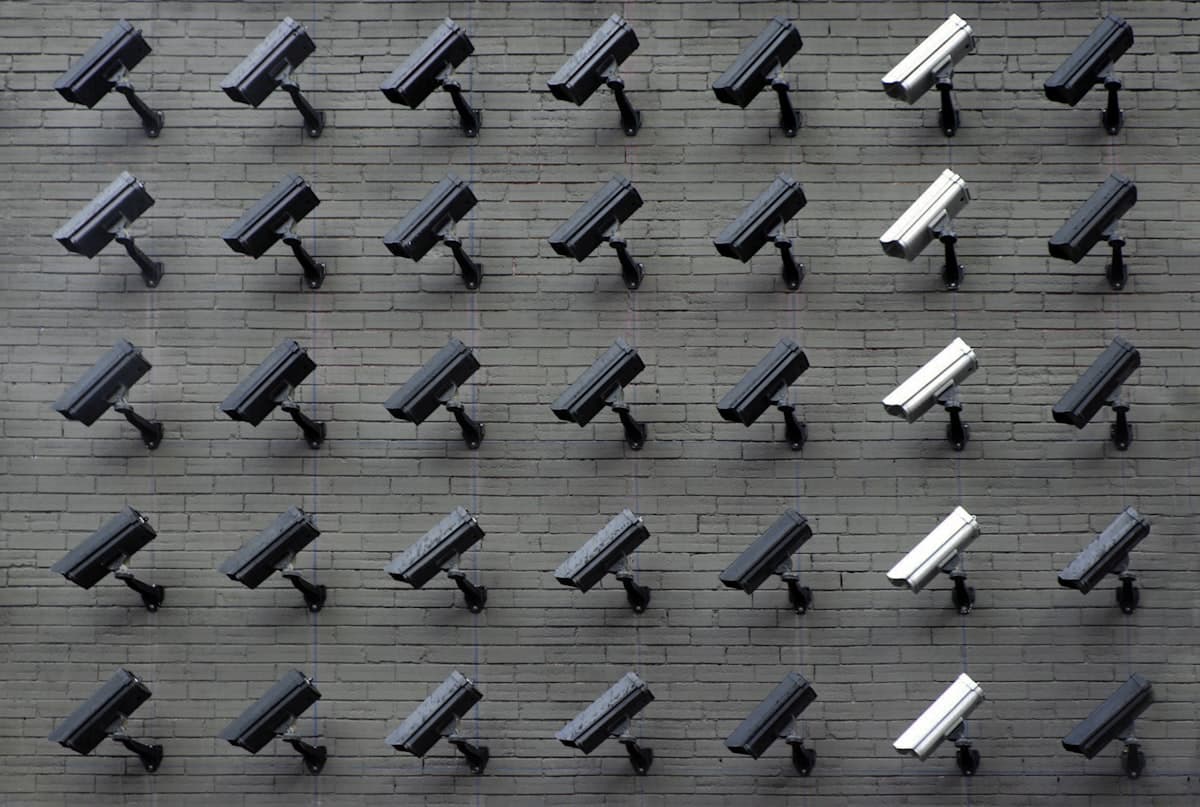 Grid of CCTV surveillance cameras mounted on a dark wall